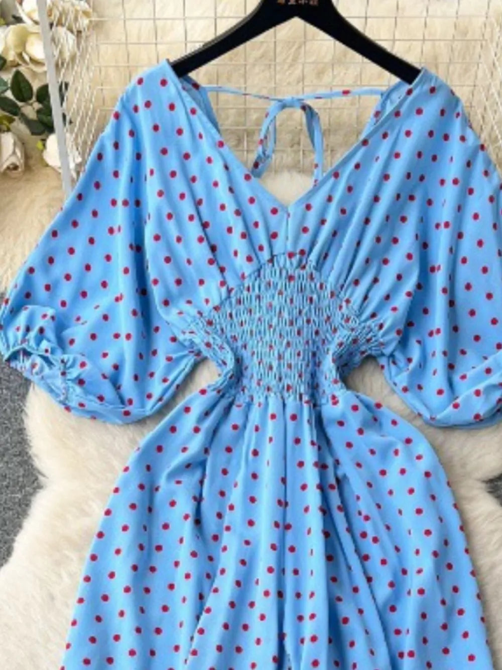 Light Blue polka dot romper with smocked waist and tie neck.