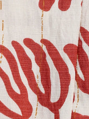 Maxi dress fabric detail with red abstract floral print and thin gold dash lines on white textured material.