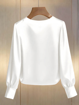 White pearl trim round neck blouse with long balloon sleeves and button cuffs.