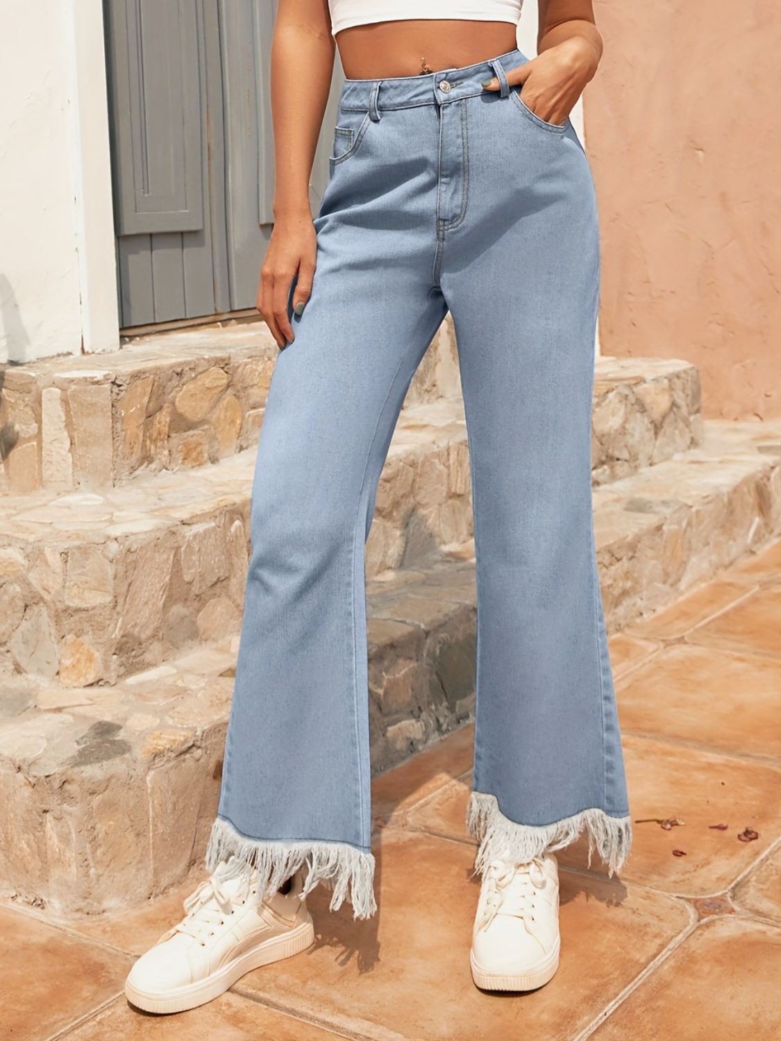 Light wash denim flare jeans with a fringed hem detail.