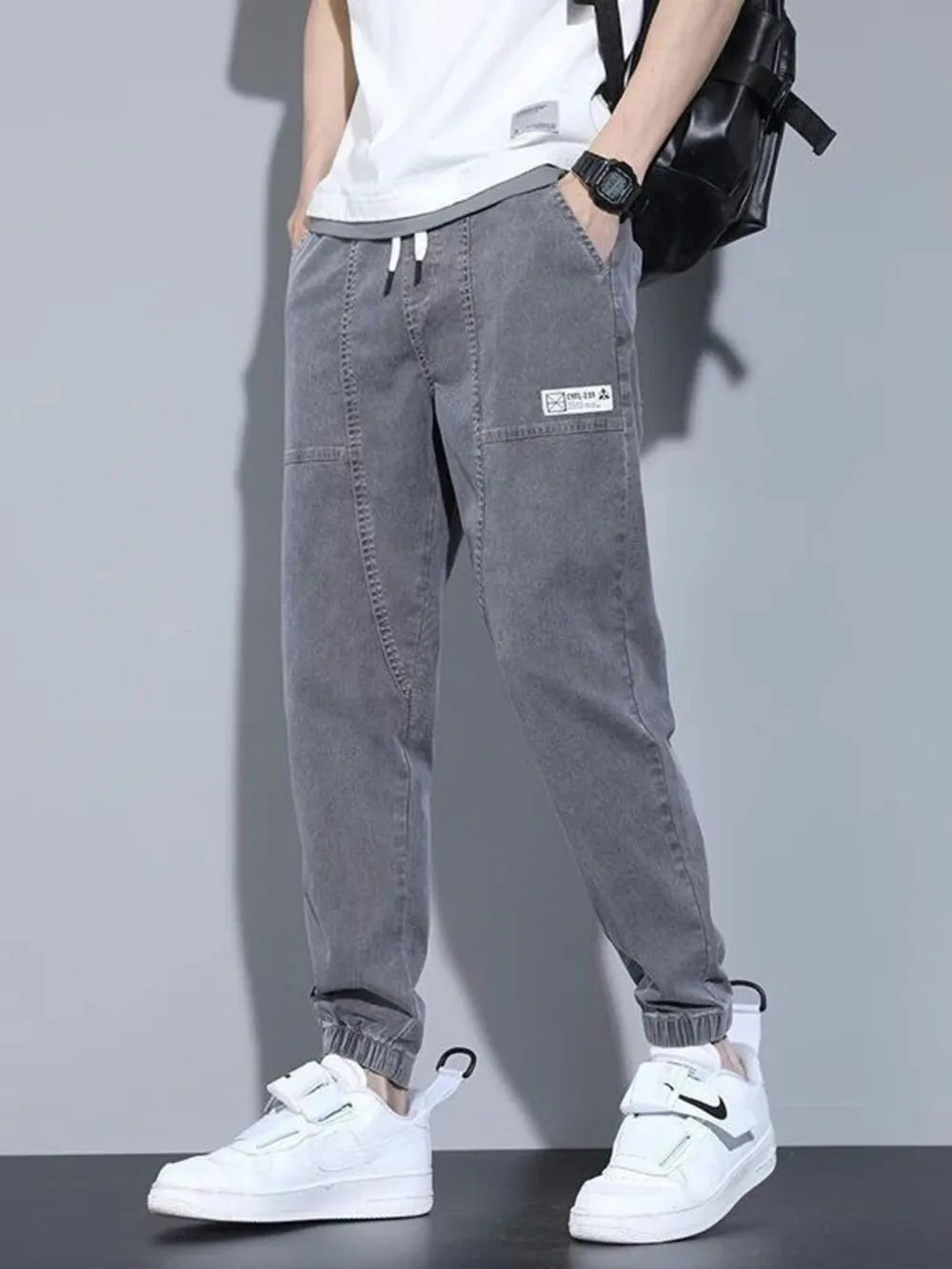 Men's gray drawstring jogger jeans with a casual fit and patch detail.