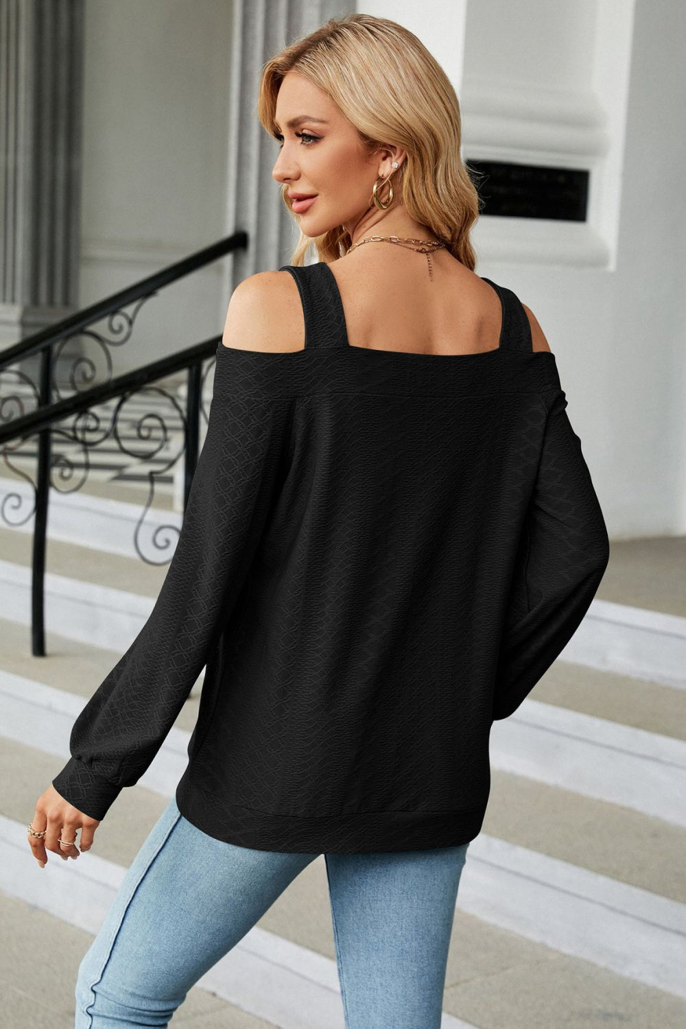 Black textured open shoulder blouse with square neckline and long sleeves.
