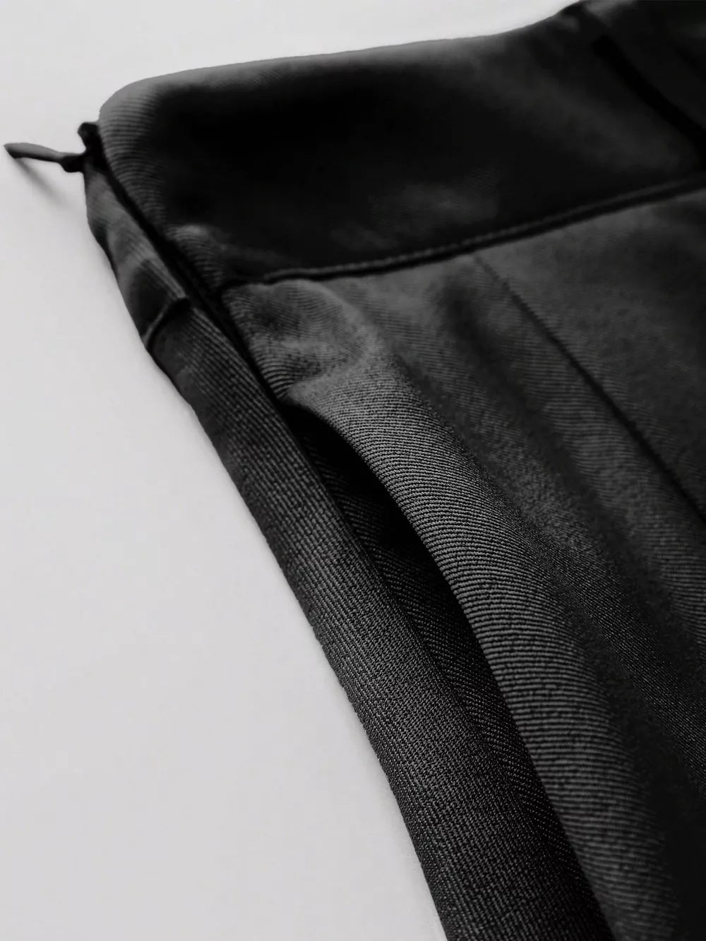 Black pleated mini skirt with defined waist and visible zipper detail.