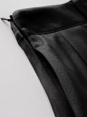 Black pleated mini skirt with defined waist and visible zipper detail.