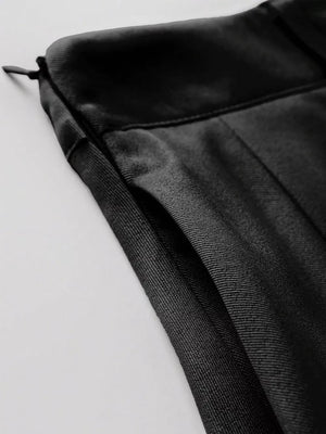 Black pleated mini skirt with defined waist and visible zipper detail.