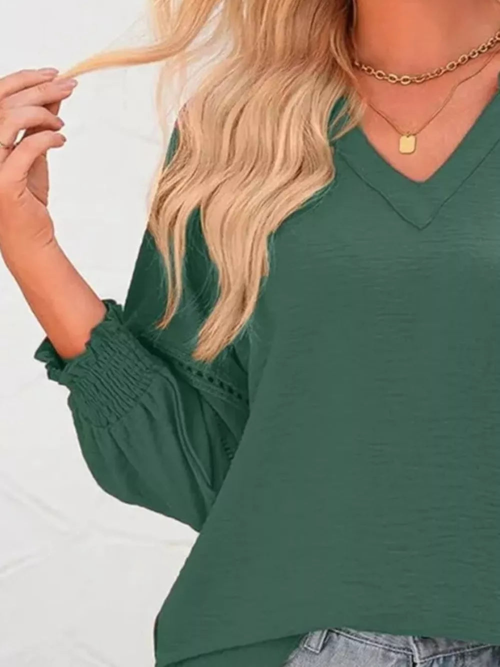 Elegant smocked long sleeve blouse in dark green polyester with V-neck and cinched cuffs.
