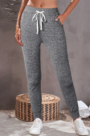 Slim-fit joggers in dark gray heather with white drawstring and pockets.