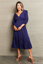 Navy backless empire waist midi dress with tiered skirt and balloon sleeves.