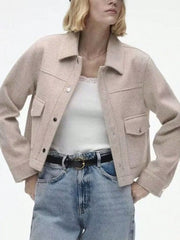 Beige trucker jacket with snap buttons, chest pockets, and collar, styled with a white cami and jeans.