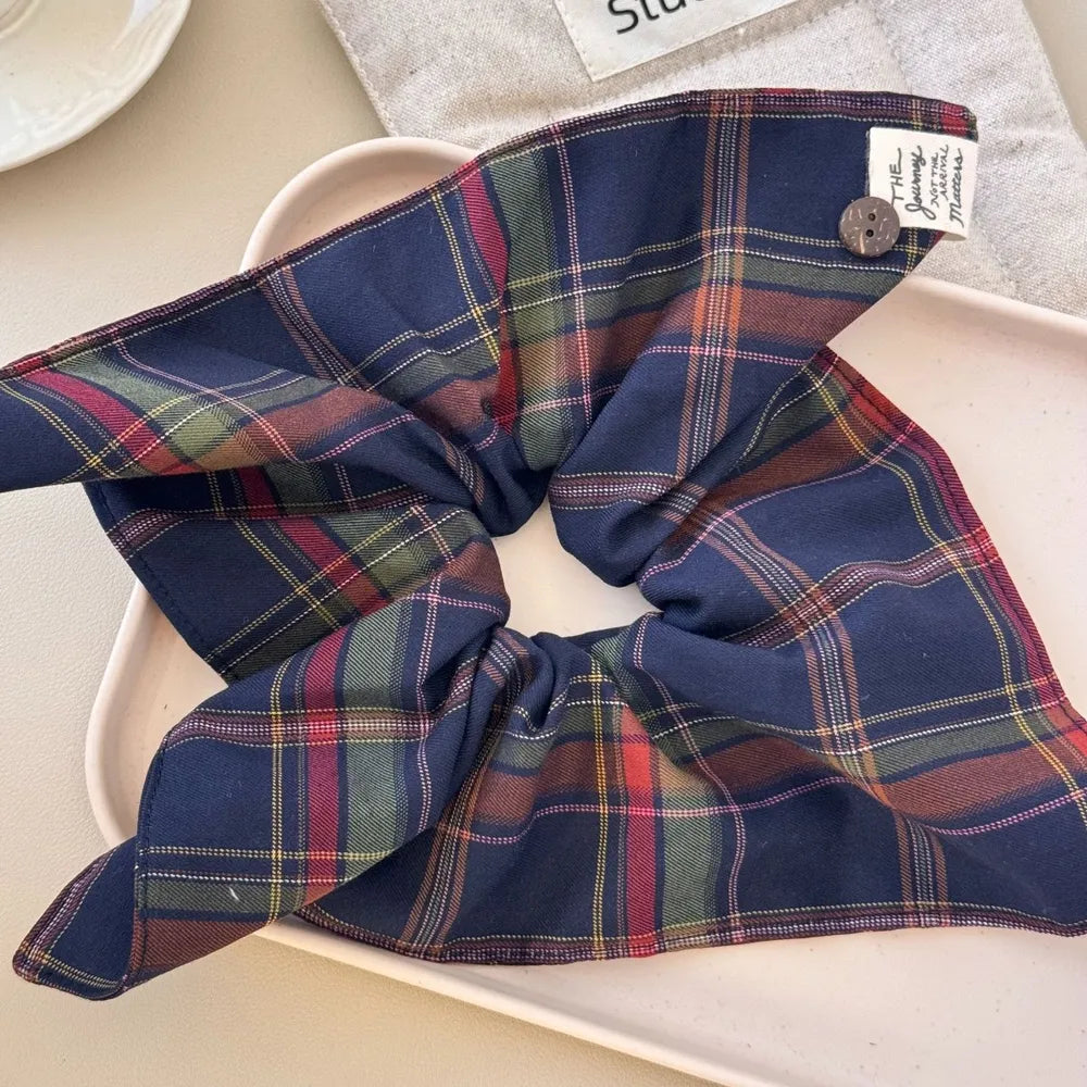 Plaid bow-tie scrunchie with button detail in navy and red tartan pattern