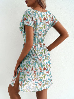 Vibrant leaf print mini dress with slit and short sleeves, white with colorful leaves.