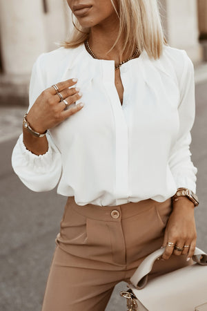 White pleated yoke blouse with button detail and gathered cuffs.