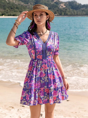 Vibrant floral eyelet mini dress with V-neck, short sleeves, and tiered skirt.