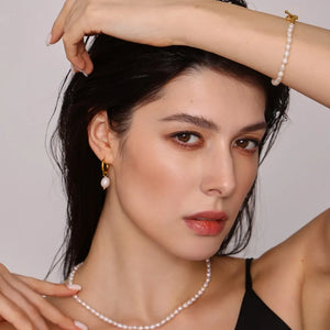 Gold pearl jewelry set with hoop earrings, necklace, and bracelet.
