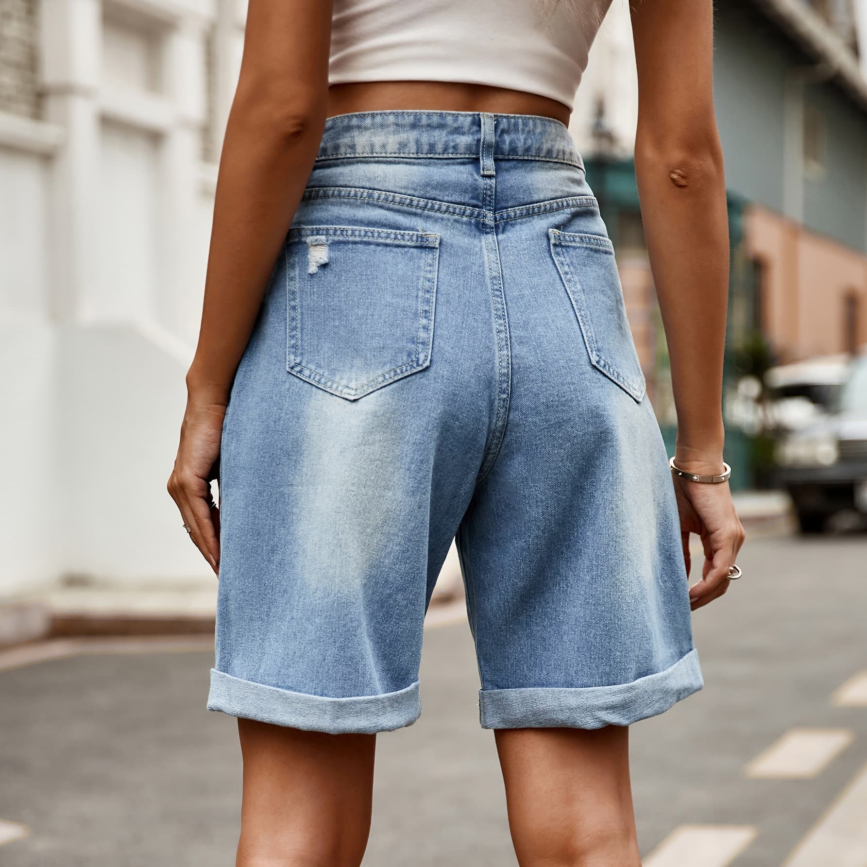 Medium wash denim shorts with rolled hems and distressed details.