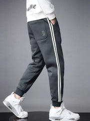 Dark gray cotton joggers with white side stripes and cuffed ankles.