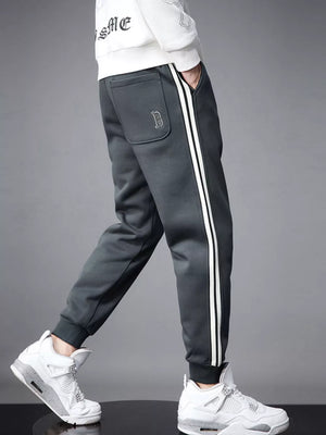 Dark gray cotton joggers with white side stripes and cuffed ankles.