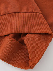 Rust cotton sweatshirt detail showing ribbed cuffs and hem.