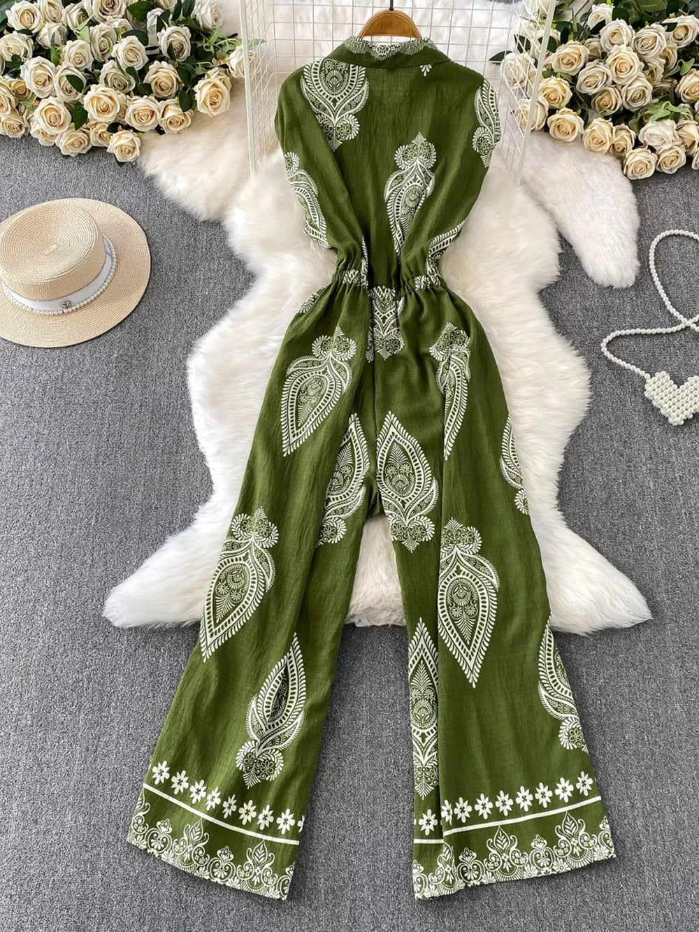 Green wide leg romper with white paisley print, collared, buttoned, and cinched waist.