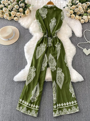 Green wide leg romper with white paisley print, collared, buttoned, and cinched waist.