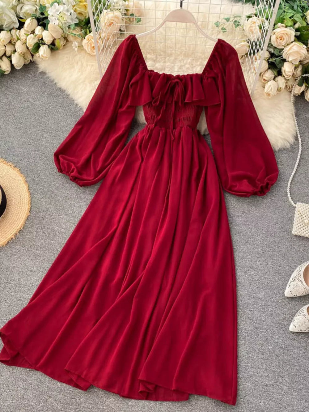 Red A-line maternity dress with square neck, ruffled trim, tie detail, smocked waist, and balloon sleeves.