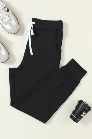 Black slim-fit joggers with drawstring and cuffed ankles.