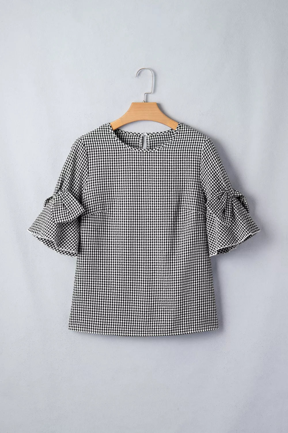 Black and white gingham polyester shirt with ruffled bow tie sleeves.