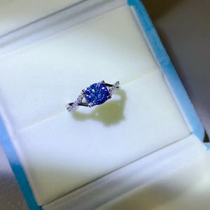 Silver twisted pavé moissanite engagement ring with blue cushion-cut center stone.