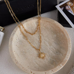 Layered 18k gold necklace with a detailed sun pendant and sparkling stones.