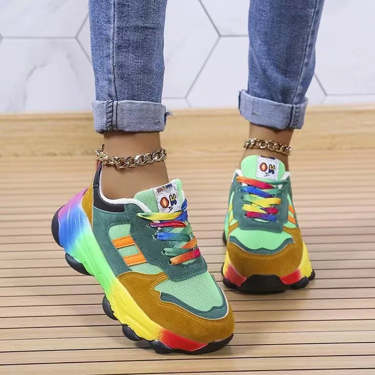 Rainbow gradient chunky sneakers with green, mustard, and red accents and colorful laces.