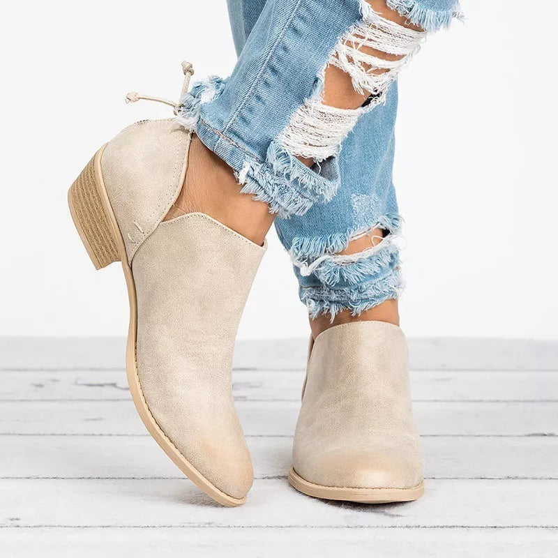 Beige V-cut pointed toe block heel boots with a tie detail at the back, styled with ripped jeans.