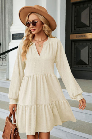 Cream textured babydoll mini dress with voluminous sleeves and tiered hem