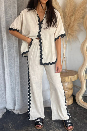 Beige linen shirt and pant set with black scalloped trim detail.