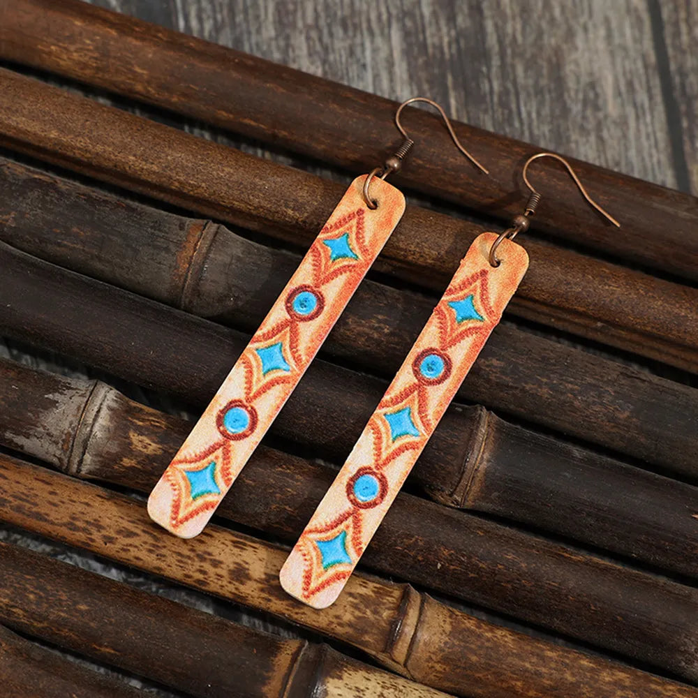 Embroidered leather dangle earrings with geometric pattern in tangerine and blue.