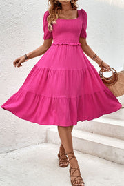 Hot pink midi dress with tiered ruffles, square neckline, puff sleeves, and smocked bodice.