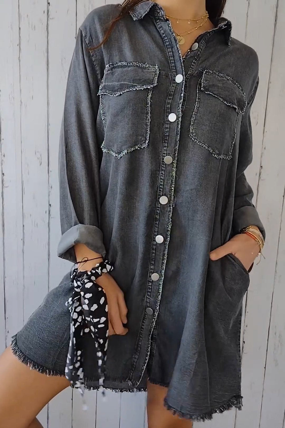 Oversized dark gray denim shirt jacket with frayed pockets and hem, buttoned front.