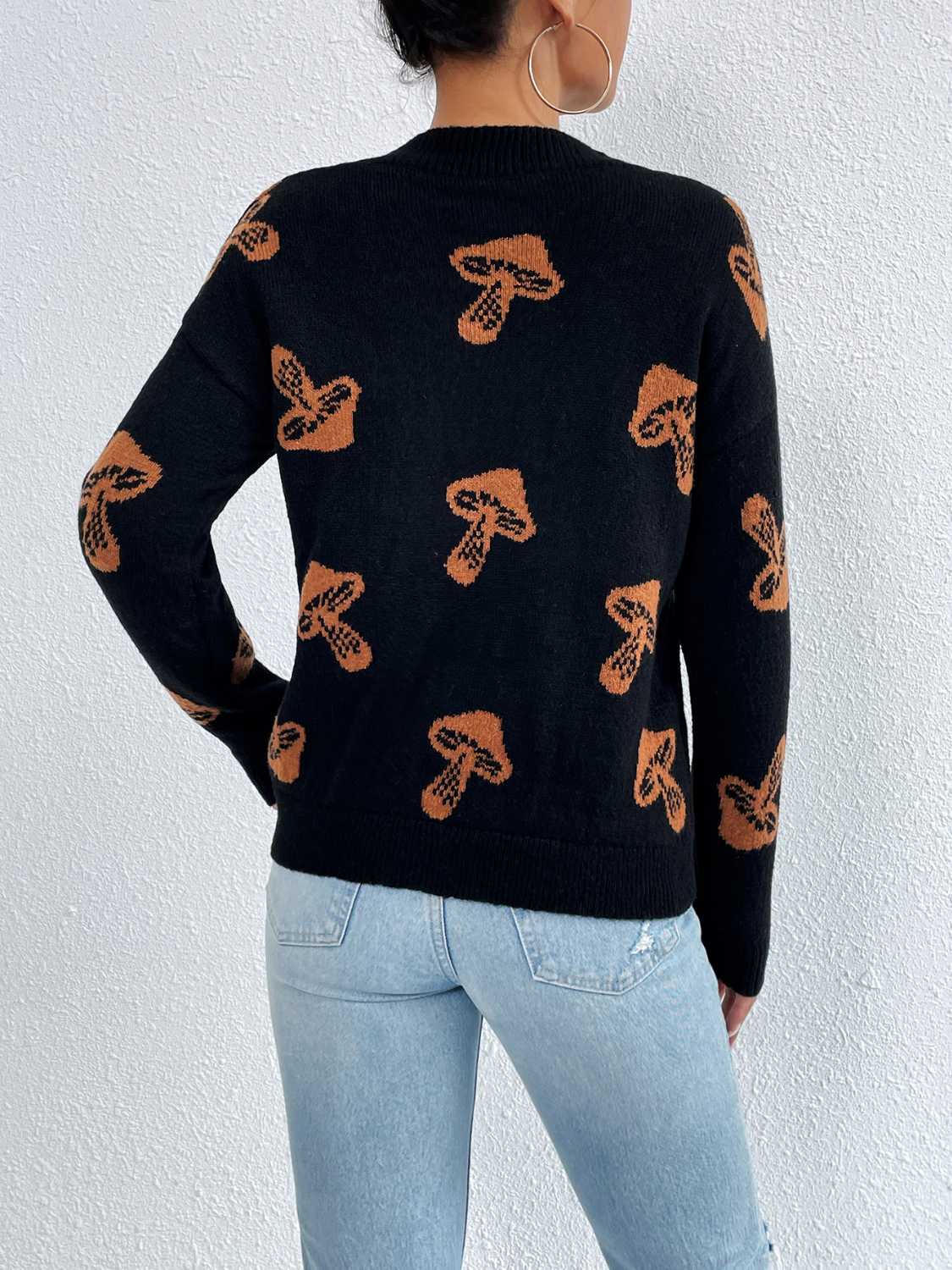 Black knit sweater with allover brown mushroom print, drop shoulder, and crew neck.