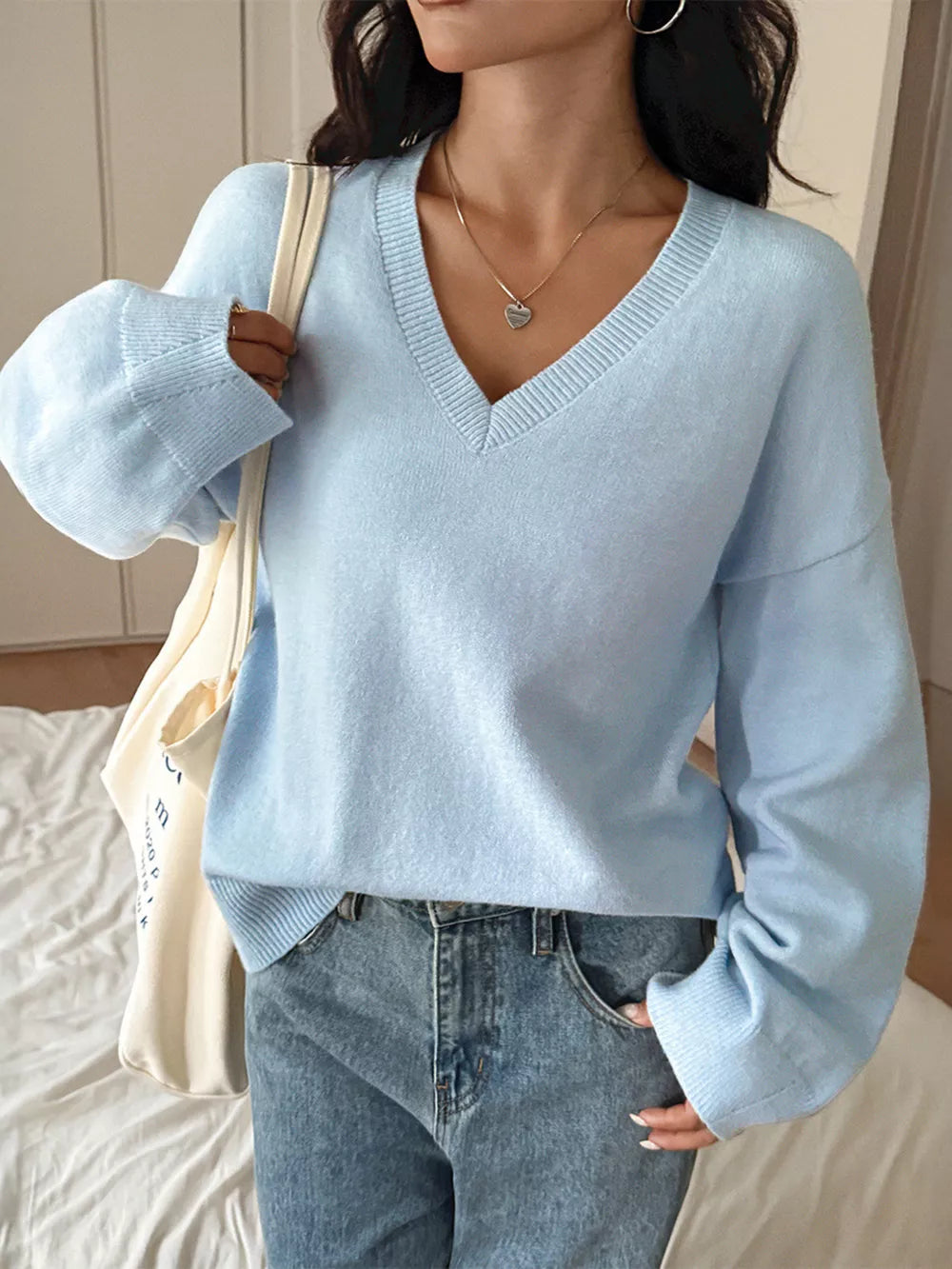 Light blue V-neck knit sweater with ribbed cuffs and neckline, acrylic fabric.