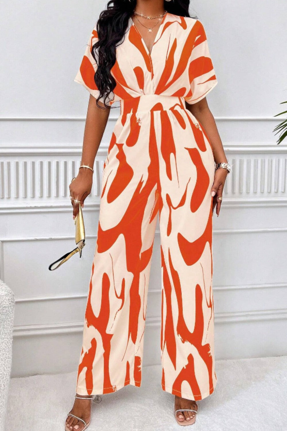 Orange and cream abstract brushstroke wide-leg jumpsuit with short sleeves and a V-neck.
