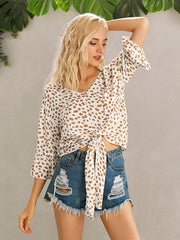 Spotted knot-front blouse with flared sleeves and a V-neck, paired with distressed denim shorts.
