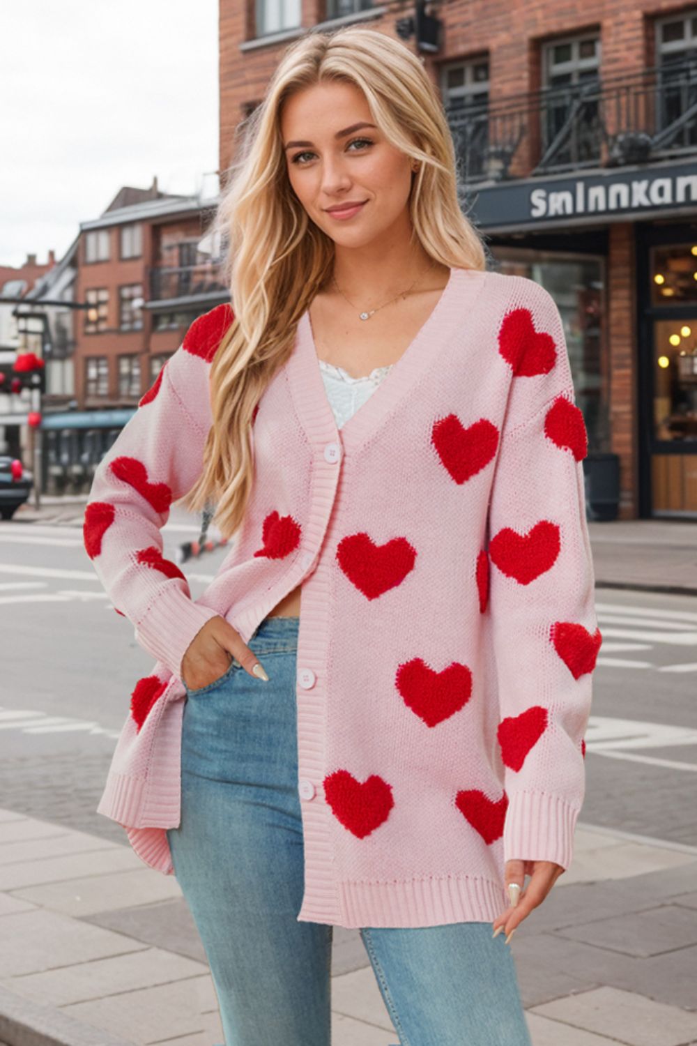 Pink knit cardigan with red heart appliqués, V-neck, button front, long sleeves.