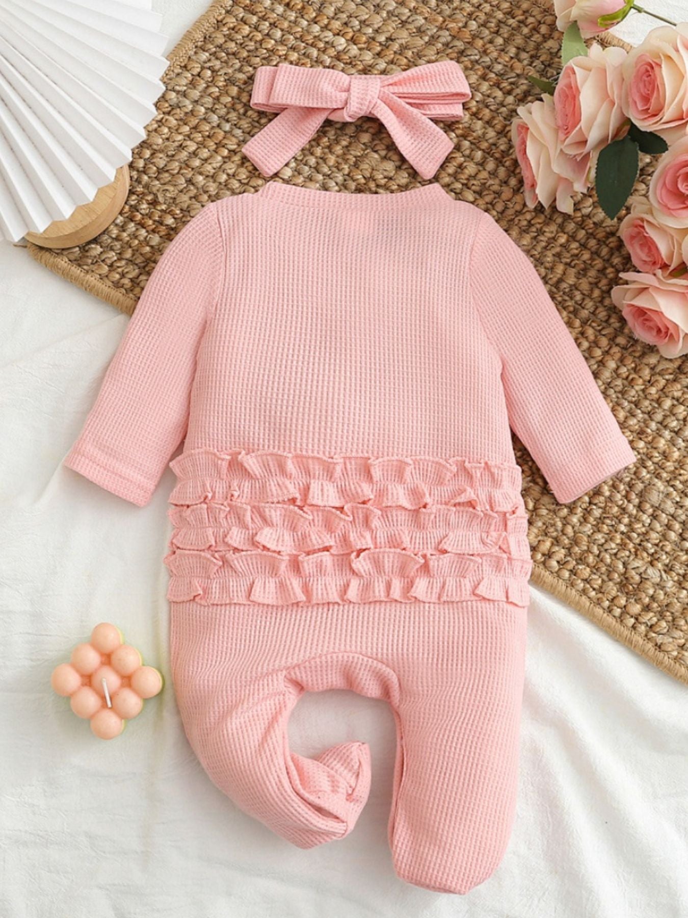 Pink waffle knit baby one-piece with ruffled waist detail and matching headband.