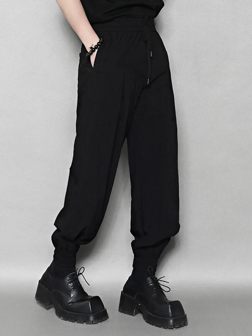 Black sweatpants with drawstring waist and ankle cuffs, featuring pockets.