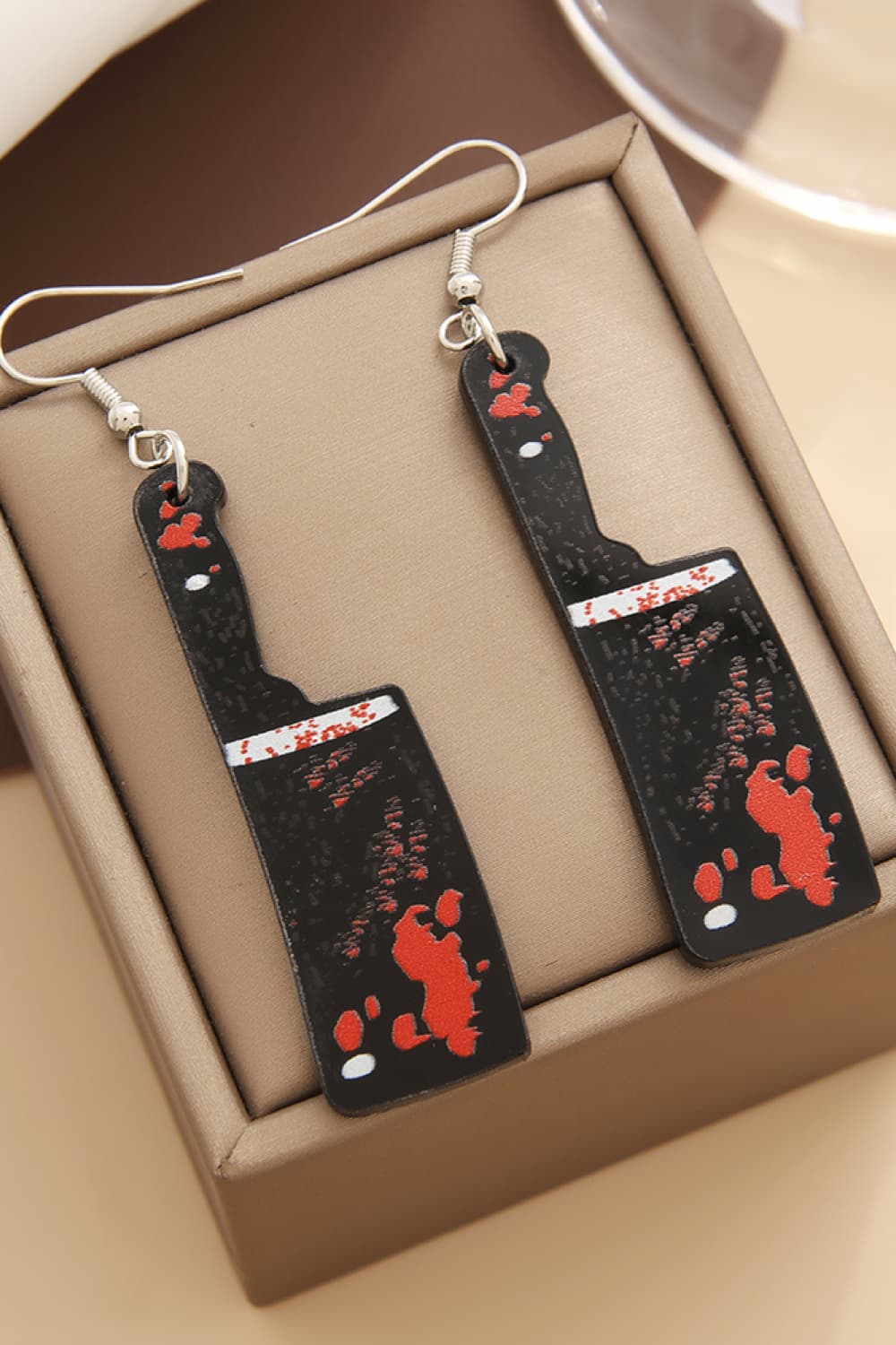 Gory blade drop earrings in black with red splatter detail and silver hooks.