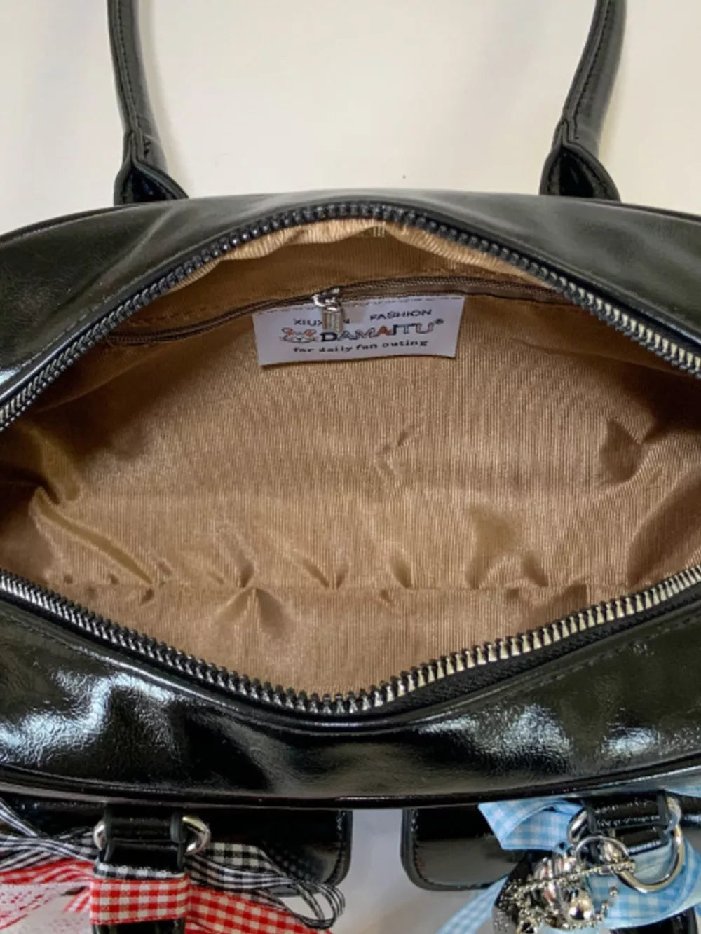 Black patent shoulder bag with ribbon embellishments and charms