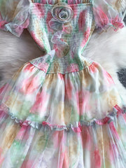 Floral tiered midi dress with smocked bodice and sheer sleeves in a pastel tie-dye print.
