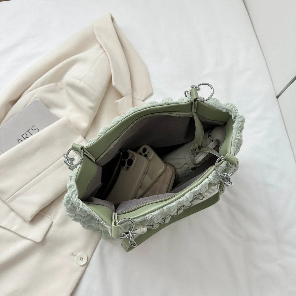 Light green textured grid pearl chain tote bag interior with phones and wallet.