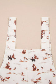 White cotton jumpsuit with desert motif, cowboys, horses, and cacti pattern.