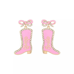 Pink cowboy boot dangle earrings with crystal trim and "Bride" text.