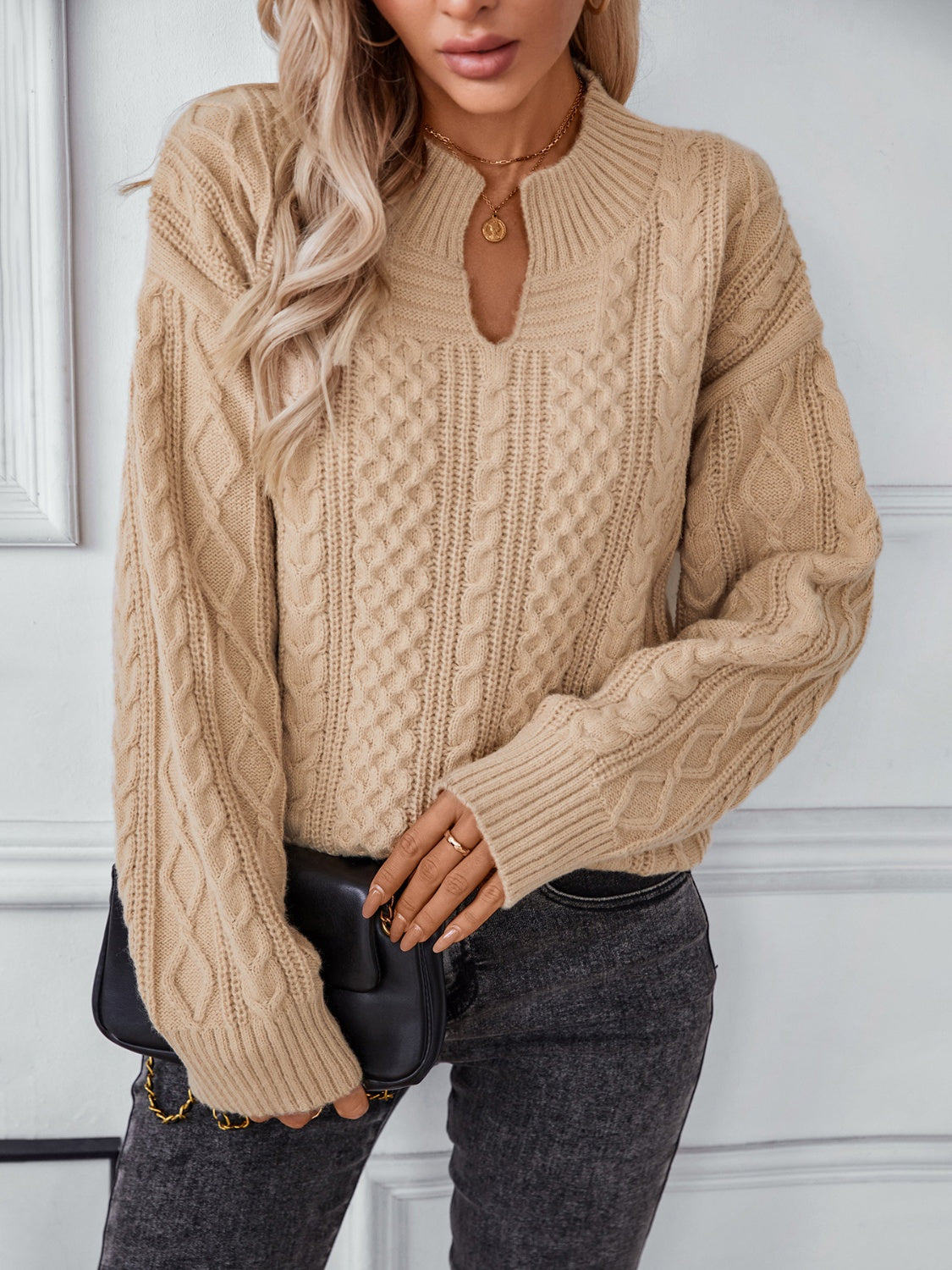 Camel cable knit sweater with keyhole neck and ribbed cuffs.